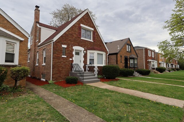 10817 S Eberhart Ave, Chicago, IL 60628 - tudor house featuring brick siding, a front lawn, and a chimney