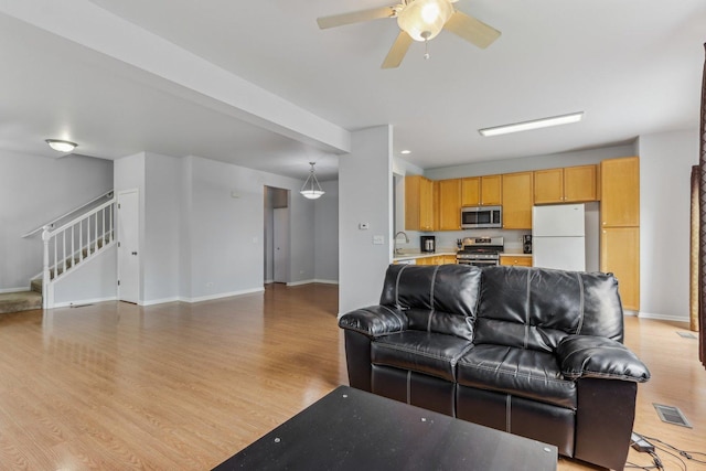 2007 S Kristina Ln, Round Lake, IL 60073 - living area featuring light wood-style floors, stairs, baseboards, and ceiling fan
