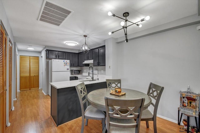 5400 Walnut Ave Unit 215, Downers Grove, IL 60515 - kitchen featuring freestanding refrigerator, light countertops, under cabinet range hood, stainless steel microwave, and a peninsula