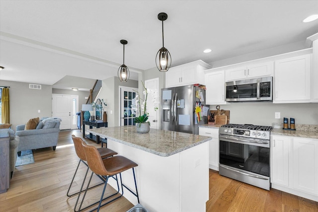 7 Connor Ct, Monticello, IL 61856 - kitchen with stainless steel appliances, open floor plan, light wood-style floors, a center island, and white cabinetry