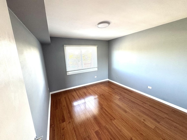 spare room with dark wood finished floors and baseboards
