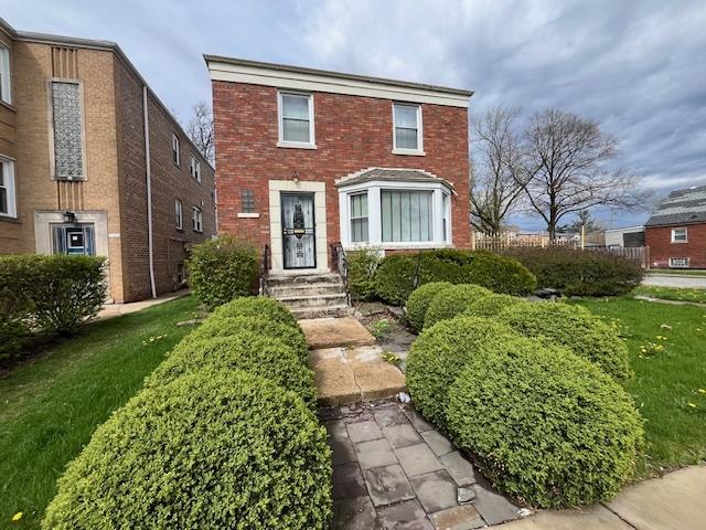 traditional home featuring brick siding and a front yard