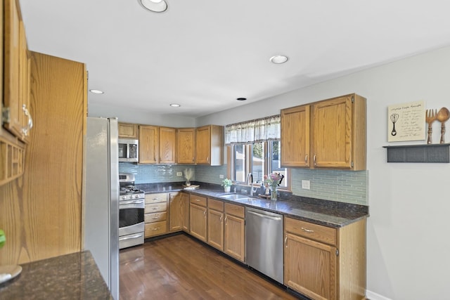 kitchen with appliances with stainless steel finishes, a sink, dark wood-type flooring, tasteful backsplash, and recessed lighting