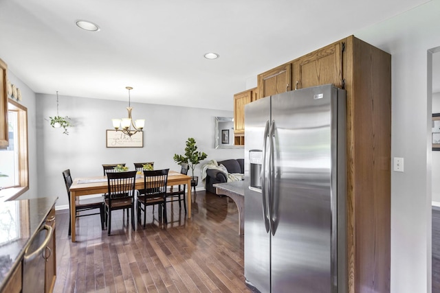kitchen with stainless steel appliances, dark wood-style floors, a chandelier, brown cabinets, and decorative light fixtures