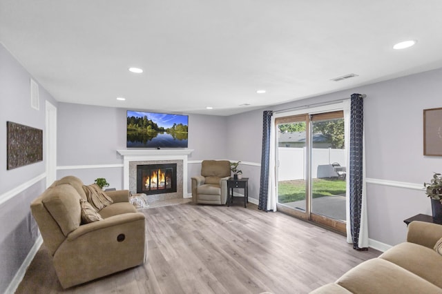 living room featuring a fireplace, baseboards, light wood-type flooring, and recessed lighting