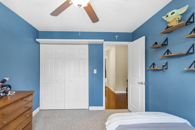 carpeted bedroom featuring a closet, baseboards, and a ceiling fan