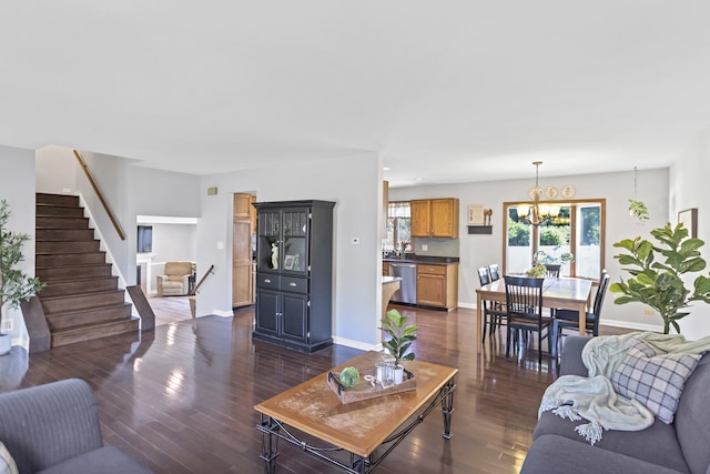 living area featuring a chandelier, stairway, dark wood-type flooring, and baseboards