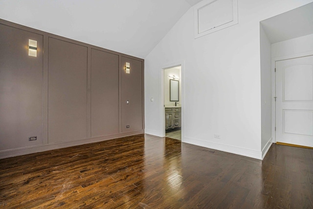 939 N Massasoit Ave, Chicago, IL 60651 - unfurnished bedroom with dark wood-style floors, a decorative wall, connected bathroom, high vaulted ceiling, and baseboards