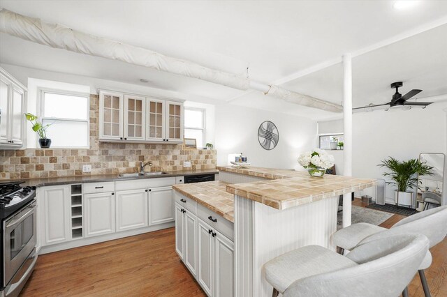 1400 W Thorndale Ave Unit G, Chicago, IL 60660 - kitchen featuring stainless steel gas stove, a sink, a breakfast bar area, backsplash, and glass insert cabinets