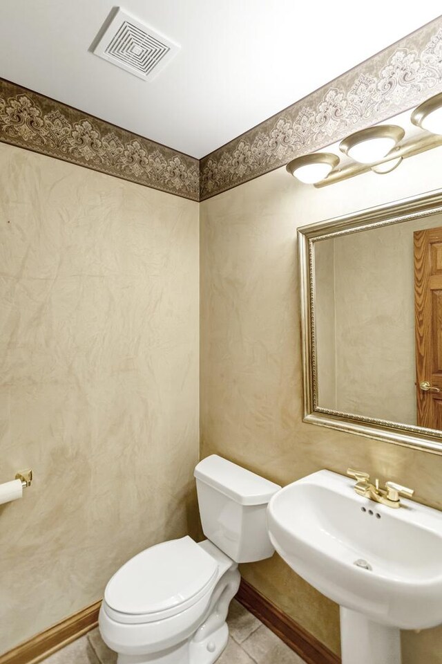 5301 S Mobile Ave, Chicago, IL 60638 - half bathroom featuring a sink, toilet, and tile patterned floors