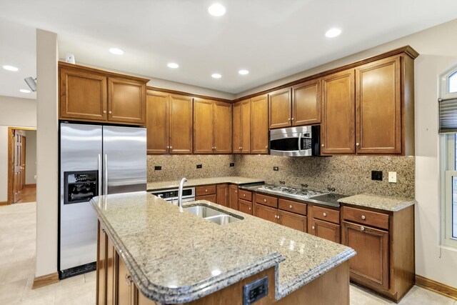5301 S Mobile Ave, Chicago, IL 60638 - kitchen with appliances with stainless steel finishes, brown cabinets, a sink, a kitchen island with sink, and light stone countertops
