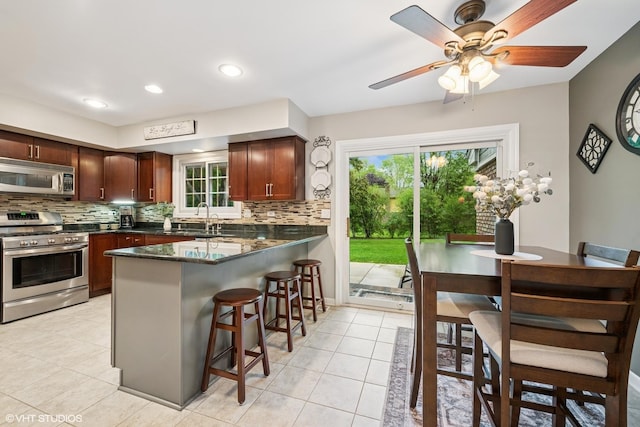 25 Lagoon Dr, Hawthorn Woods, IL 60047 - kitchen featuring appliances with stainless steel finishes, a kitchen bar, decorative backsplash, a peninsula, and light tile patterned floors