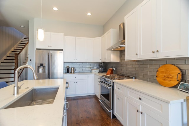 kitchen with high quality appliances, wall chimney range hood, a sink, tasteful backsplash, and recessed lighting