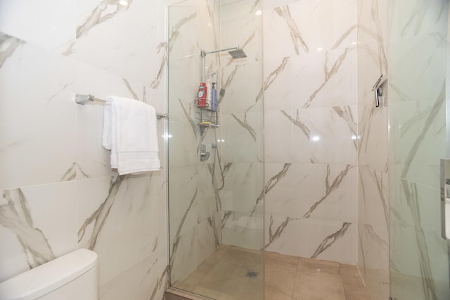 bathroom featuring toilet and a marble finish shower