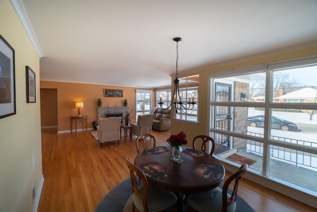 1841 Hawthorne Ave, Westchester, IL 60154 - dining area featuring ornamental molding, a stone fireplace, light wood finished floors, and a chandelier