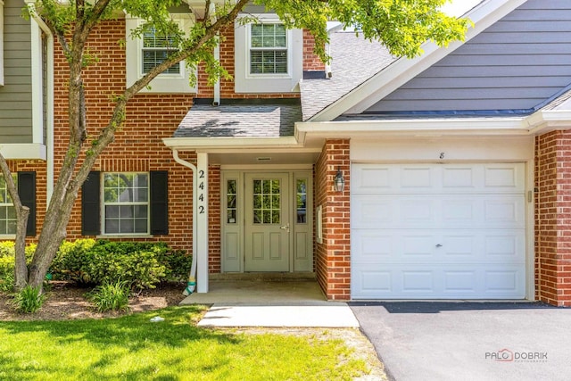 2442 Charleston Dr Unit 5, Schaumburg, IL 60193 - property entrance featuring brick siding, a shingled roof, asphalt driveway, and an attached garage