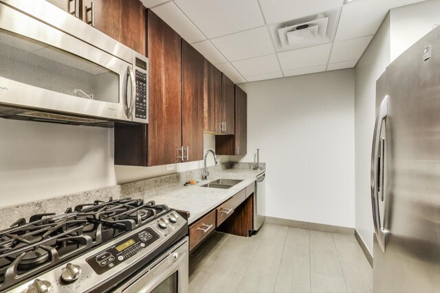 1160 S Michigan Ave Unit 1503, Chicago, IL 60605 - kitchen with appliances with stainless steel finishes, a sink, a drop ceiling, baseboards, and dark brown cabinetry