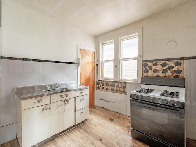 1745 E 85th St, Chicago, IL 60617 - kitchen featuring stainless steel countertops, black range with gas cooktop, a sink, light wood-type flooring, and tile walls