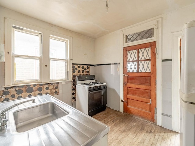 1745 E 85th St, Chicago, IL 60617 - kitchen featuring gas range oven, a sink, light wood-style floors, freestanding refrigerator, and light countertops