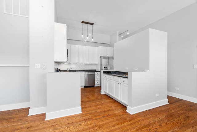 4751 N Artesian Ave Unit 401, Chicago, IL 60625 - kitchen with appliances with stainless steel finishes, dark countertops, backsplash, white cabinets, and hanging light fixtures