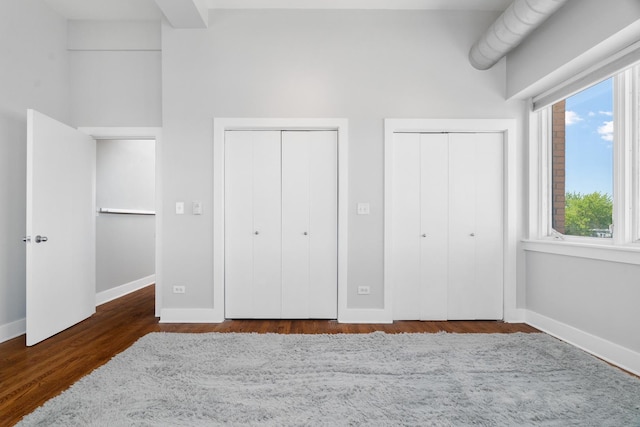 4751 N Artesian Ave Unit 401, Chicago, IL 60625 - unfurnished bedroom with multiple closets, baseboards, multiple windows, wood finished floors, and a high ceiling