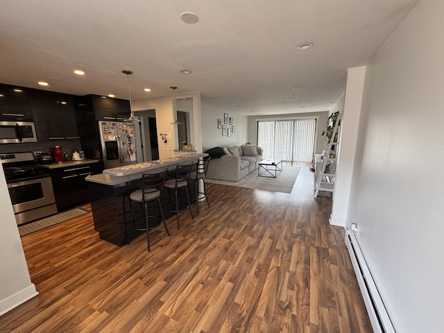 kitchen featuring stainless steel appliances, a kitchen breakfast bar, a baseboard heating unit, modern cabinets, and open floor plan