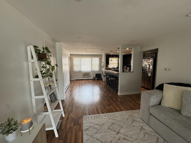 living area with wood finished floors, baseboard heating, and baseboards