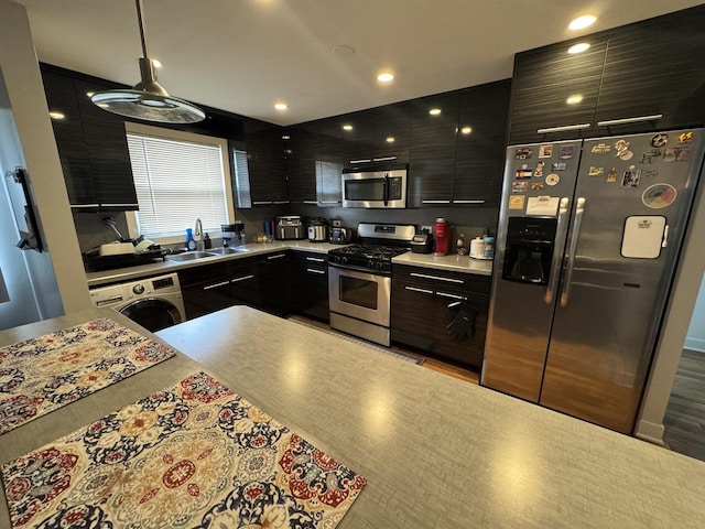 kitchen featuring stainless steel appliances, washer / clothes dryer, a sink, light countertops, and modern cabinets