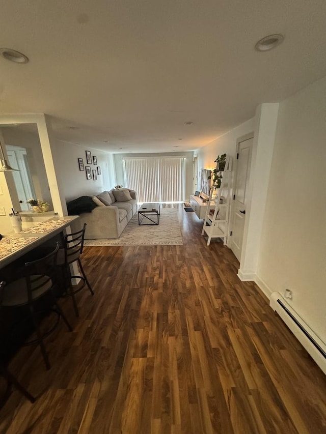 living room featuring baseboard heating, dark wood-type flooring, and baseboards