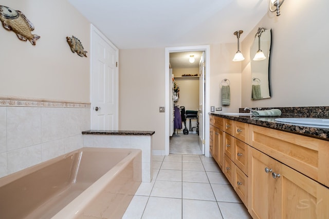 full bath featuring double vanity, a bath, and tile patterned floors