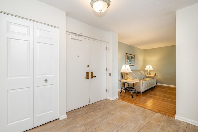 foyer entrance featuring light wood finished floors and baseboards