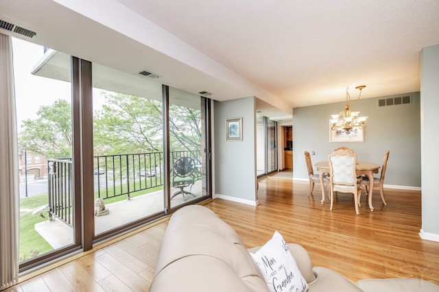 living area with a chandelier, plenty of natural light, light wood finished floors, and baseboards