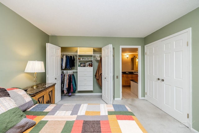 bedroom featuring light carpet, ensuite bathroom, baseboards, and a closet