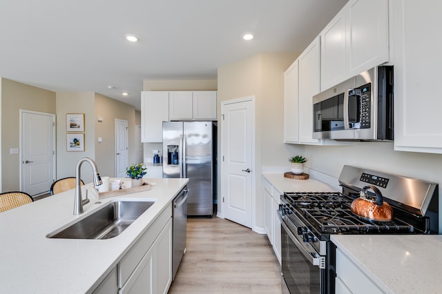 kitchen featuring appliances with stainless steel finishes, a sink, recessed lighting, white cabinets, and light stone countertops
