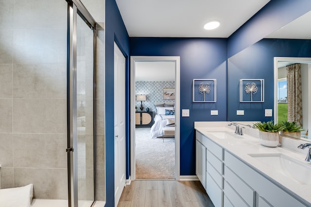 bathroom featuring wood finished floors, a shower stall, connected bathroom, and double vanity
