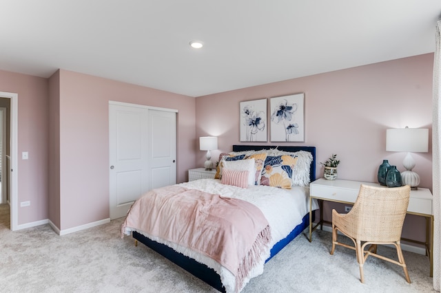 bedroom with a closet, light colored carpet, and baseboards