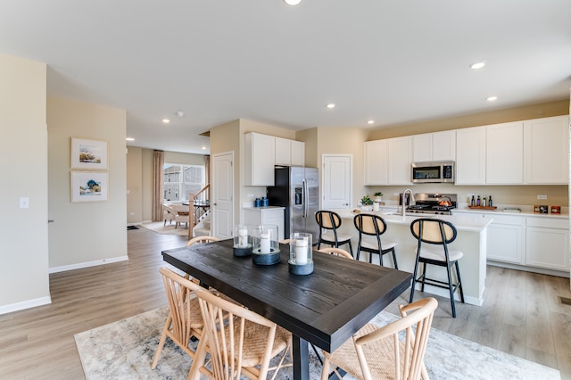 dining room featuring stairway, light wood-style flooring, baseboards, and recessed lighting