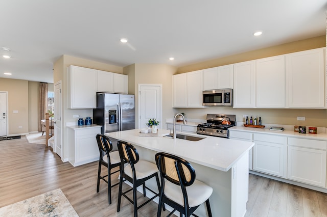 kitchen featuring a sink, stainless steel appliances, light wood-style flooring, a kitchen breakfast bar, and an island with sink