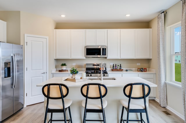 kitchen with appliances with stainless steel finishes, light wood-type flooring, light countertops, plenty of natural light, and recessed lighting