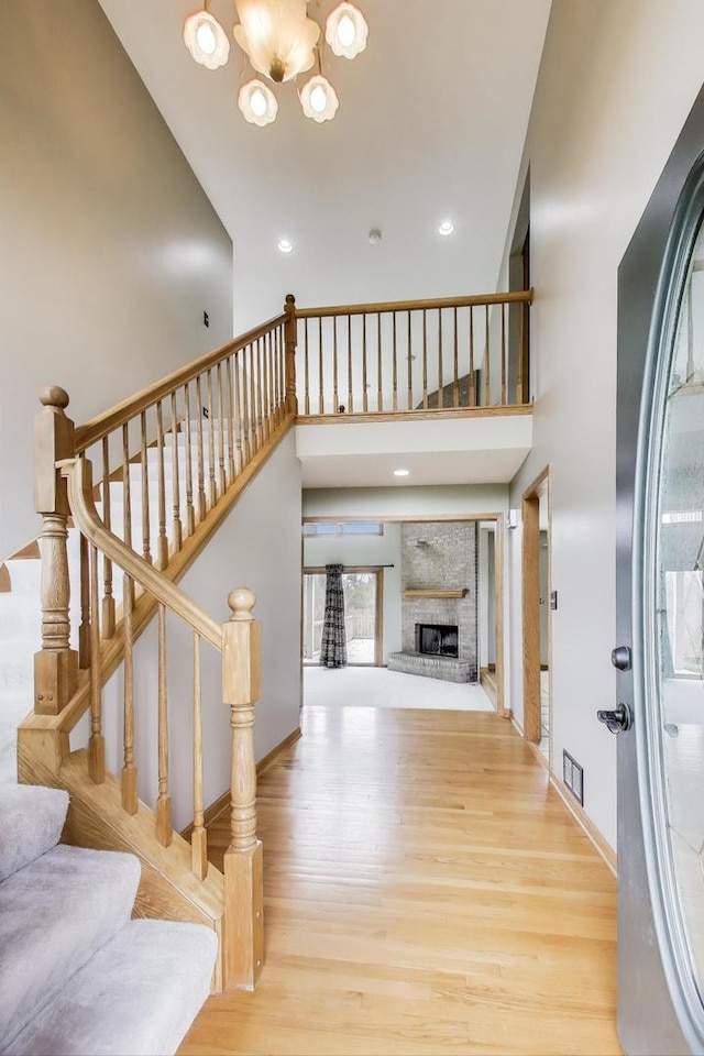 23883 W Sarah Ct, Antioch, IL 60002 - entryway featuring wood finished floors, a chandelier, a high ceiling, stairs, and a fireplace