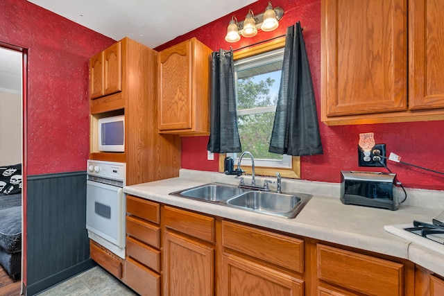 341 N Center St, Braidwood, IL 60408 - kitchen with oven, a sink, light countertops, a wainscoted wall, and brown cabinetry