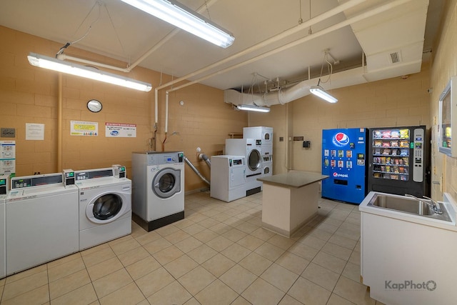 3021 S Michigan Ave Unit 102, Chicago, IL 60616 - shared laundry featuring independent washer and dryer, concrete block wall, stacked washer and clothes dryer, and light tile patterned flooring