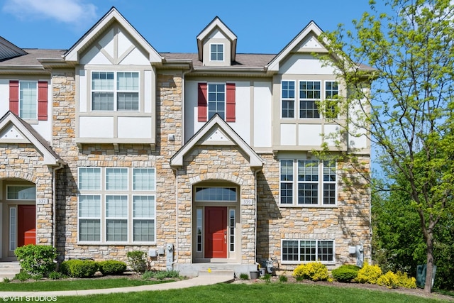 view of front of home featuring stone siding, stucco siding, and a front yard