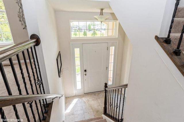 foyer entrance with healthy amount of natural light, stairway, and tile patterned floors