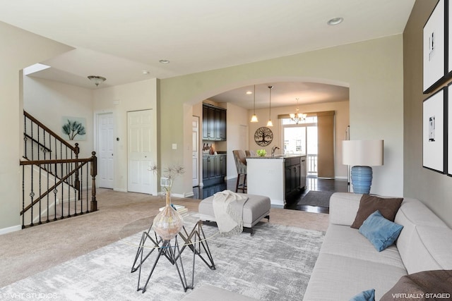 living area with arched walkways, stairway, light carpet, recessed lighting, and baseboards