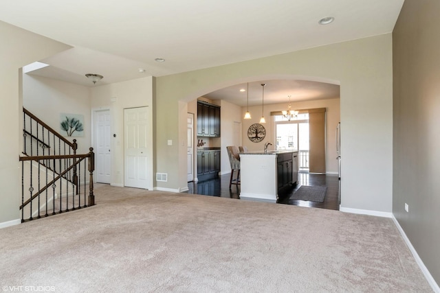 unfurnished living room with arched walkways, dark colored carpet, baseboards, and recessed lighting