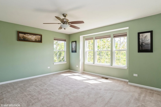 carpeted spare room with baseboards and a ceiling fan