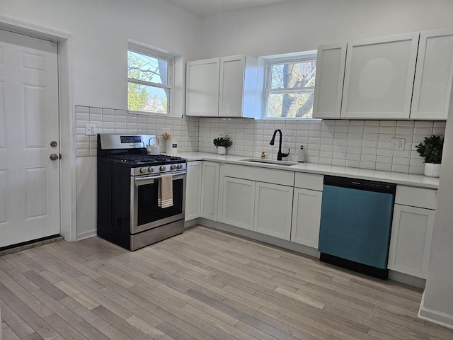 4336 W Gladys Ave, Chicago, IL 60624 - kitchen with stainless steel gas stove, dishwashing machine, a sink, light wood finished floors, and decorative backsplash
