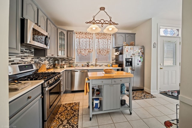 4619 N Springfield Ave, Chicago, IL 60625 - kitchen with appliances with stainless steel finishes, gray cabinets, backsplash, butcher block countertops, and light tile patterned floors