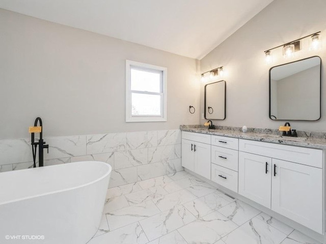 35491 N Kenneth Dr, Lake Villa, IL 60046 - bathroom featuring marble finish flooring, lofted ceiling, double vanity, a freestanding tub, and a wainscoted wall